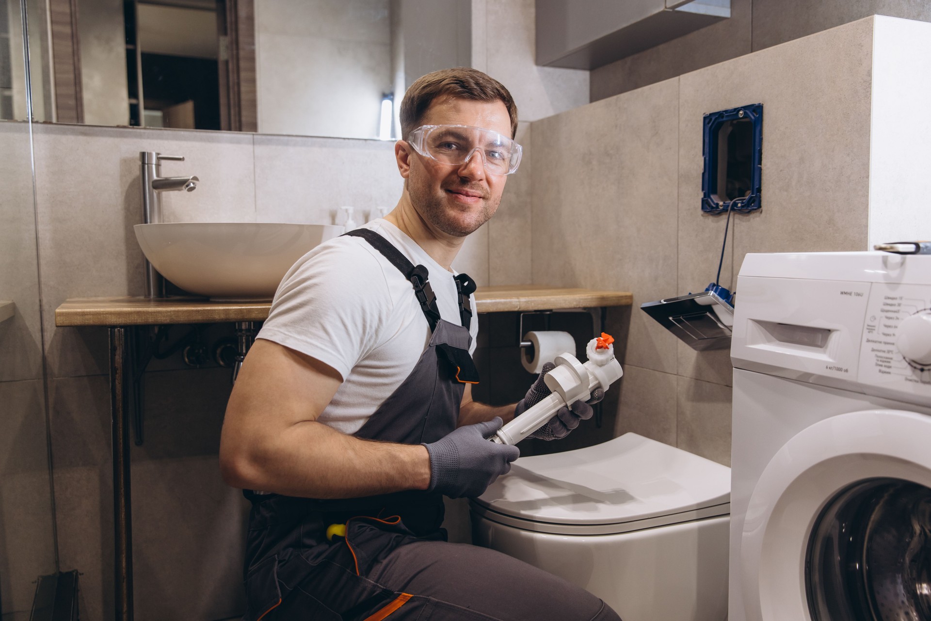 Professional plumber working on toilet fixture in modern bathroom